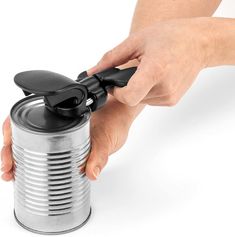 a person is holding a can opener with one hand and pulling the lid off it