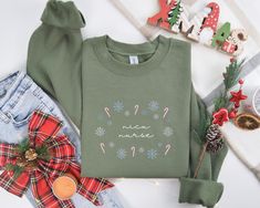 a green sweater with the words merry written on it next to christmas decorations and other items