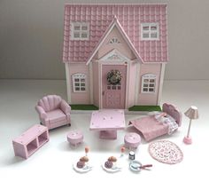 a pink dollhouse with furniture and accessories on the floor in front of a white wall