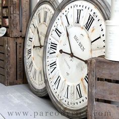 two large white clocks sitting next to each other on top of wooden pallet boxes