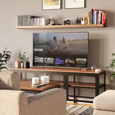 a flat screen tv sitting on top of a wooden shelf in a living room next to two couches