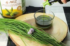 someone is pouring green tea into a glass on top of a wooden slice with grass