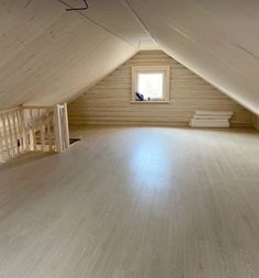 an empty attic with wood floors and white walls