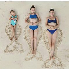 three women in bikinis laying on the sand with their arms around each other and smiling