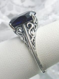 Blue Sapphire Sterling Silver Ring Swan Design #D190 Introducing our Blue Sapphire Sterling Silver Ring, Swan Design #D190 - a mesmerizing fusion of Art Deco elegance and contemporary flair. Crafted with precision and passion, this stunning ring boasts a radiant man-made blue sapphire gemstone, set within a sterling silver filigree setting that exudes sophistication and charm. At the heart of this exquisite piece lies a faceted simulated oval gemstone, measuring 12mm x 10mm, captivating with its Elegant Sapphire Ring With Intricate Design, Elegant Adjustable Filigree Ring For Formal Occasions, Elegant Sapphire Jewelry With Intricate Design, Elegant Sterling Silver Jewelry With Artistic Design, Elegant Blue Sapphire Ring, Unique Blue Sapphire Ring For Wedding, Elegant Blue Sapphire Ring For Formal Occasions, Elegant Adjustable Filigree Ring For Wedding, Elegant Artistic Design Jewelry For Anniversary