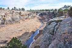 a bridge over a river in the middle of a rocky area with trees on both sides