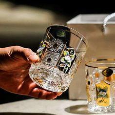 a person holding a glass in their hand next to two glasses on a counter top