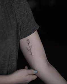 a woman's arm with a single flower tattoo on the left side of her arm