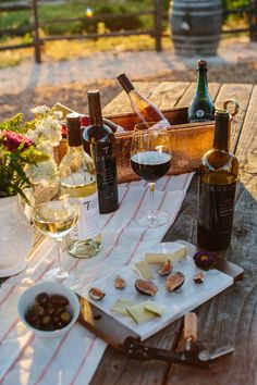 wine and cheese are sitting on a picnic table