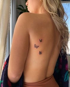 the back of a woman's body with three butterflies on her left shoulder and chest