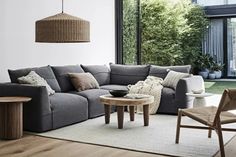 a living room filled with lots of furniture next to a large glass window and wooden flooring