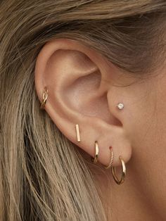 a close up of a woman's ear with two small gold hoops on it