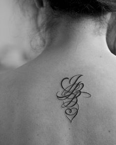 the back of a woman's neck with a tattoo design on her left shoulder