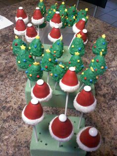 christmas cupcakes with santa hats and trees on them sitting on a counter top