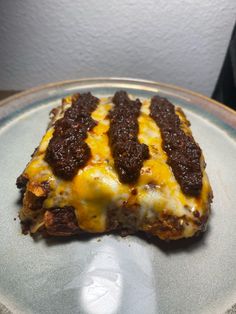 a piece of pizza on a plate with cheese and meat toppings, ready to be eaten