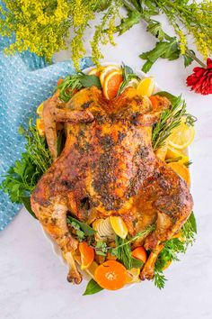 a whole chicken on a platter with oranges and herbs