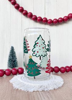 a glass jar with christmas trees painted on it