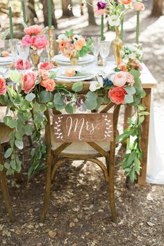 a wooden table topped with flowers and greenery