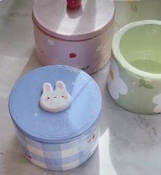 two tins sitting on top of a counter next to each other, one with a bunny face