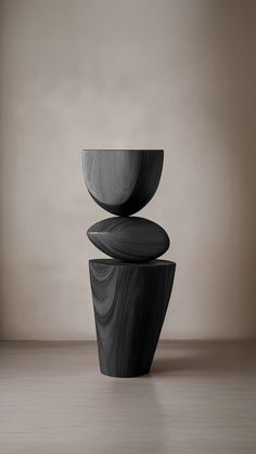 three black bowls stacked on top of each other in front of a beige wall and floor