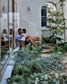 two people and a dog sitting on a window sill in front of a building