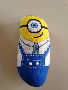 a hand painted rock with an image of a minion in overalls on it