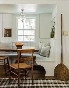 a dining room table and chairs with a bench in front of the window next to it