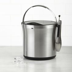 a stainless steel ice bucket with tongs and an ice scooper next to it