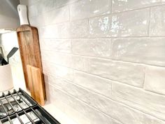 a stove top oven sitting next to a wooden cutting board on the side of a wall