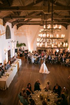 a bride and groom are dancing in the middle of a large room full of people