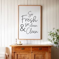 a wooden cabinet sitting in front of a white wall with a framed poster above it