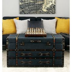 a trunk coffee table with chess pieces on it in front of a couch and map