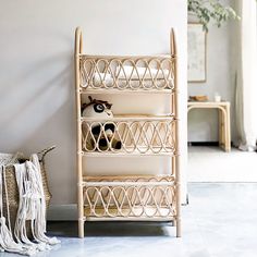 a bamboo shelf with baskets on it in a room next to a chair and table