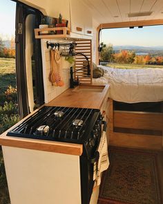 a kitchen area with an oven, stove and bed in the back ground next to a window