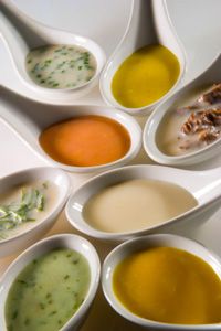 six spoons with different types of soup in them