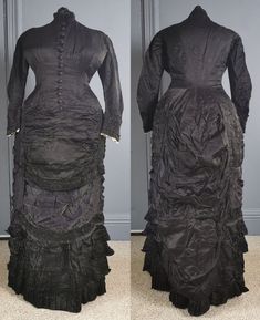 A superb, gothic Victorian antique bustle dress for mourning, dating to the early 1880s / natural form era - excellent condition, and a rare larger size. One piece, in a glossy two tone silk, black, the reverse in purple, the dress reflecting subtle purple tones. Closely fitted to the body, the bodice boned, fastening in the front with woven dome buttons in purple from neck to hip. Small collar, and a small waist patch pocket. Long fitted sleeves, with gathered cuffs and lace trim on the inner e Black Victorian Gothic Dress With Historical Design, Black Gothic Victorian Dress With Historical Design, Black Victorian Dress With Long Sleeves, Black Long Sleeve Victorian Dress, Historical Victorian Dress With Ruffles For Formal, Historical Victorian Dress With Ruffles For Formal Occasion, Black Historical Victorian Costume Dress, Formal Historical Victorian Dress With Ruffles, Black Victorian Dress With Ruffles