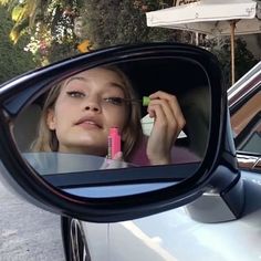 a woman in the side view mirror of a car