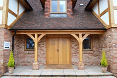 a wooden door in front of a brick building with two planters next to it