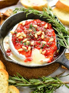 a pan filled with cheese and sauce on top of crackers next to sliced bread