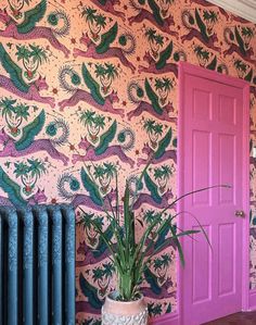 a room with a pink door and colorful wallpaper