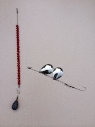 two birds sitting on top of a blue beaded necklace next to a hook with beads