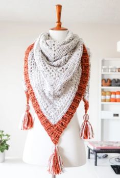 a white mannequin with an orange and gray scarf on it