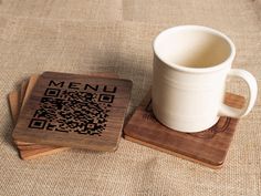 a wooden coaster with a qr code on it next to a cup of coffee