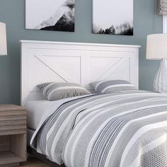 a white bed with two pictures on the wall above it and a nightstand next to it