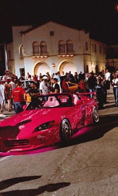 a red sports car driving down a street at night