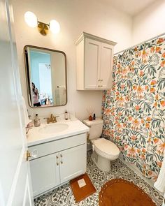 a bathroom with floral wallpaper and tile flooring, including a mirror above the toilet