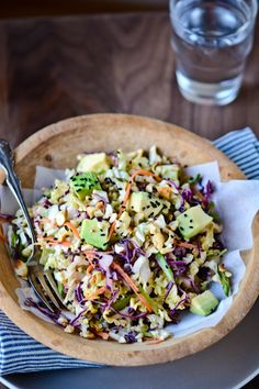 a wooden bowl filled with salad and a fork