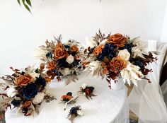 two vases filled with flowers sitting on top of a white table covered in cloth