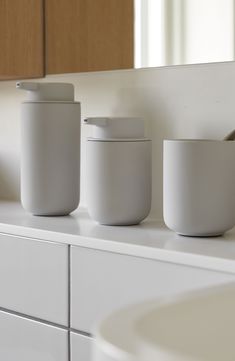 three white containers sitting on top of a counter