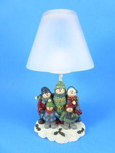 a small lamp with three snowmen on it